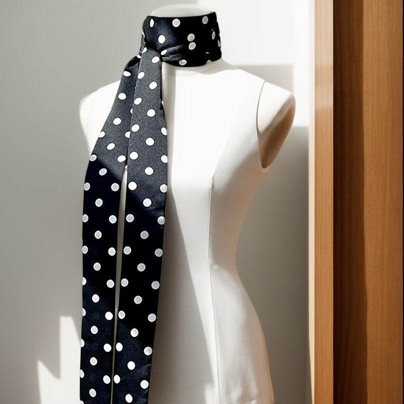 Mannequin wearing a black scarf with white polka dots against a neutral background