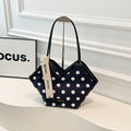 Black polka dot shoulder bag with white trim and unique geometric shape, featuring branded ribbon detail
