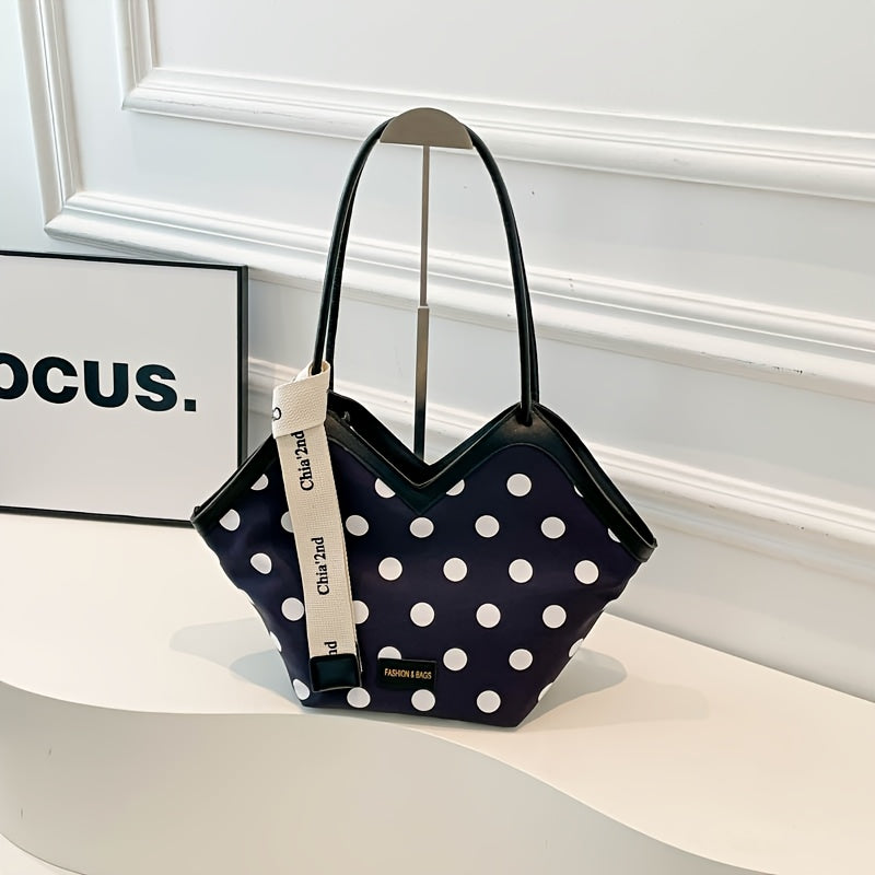 Black polka dot shoulder bag with white trim and unique geometric shape, featuring branded ribbon detail