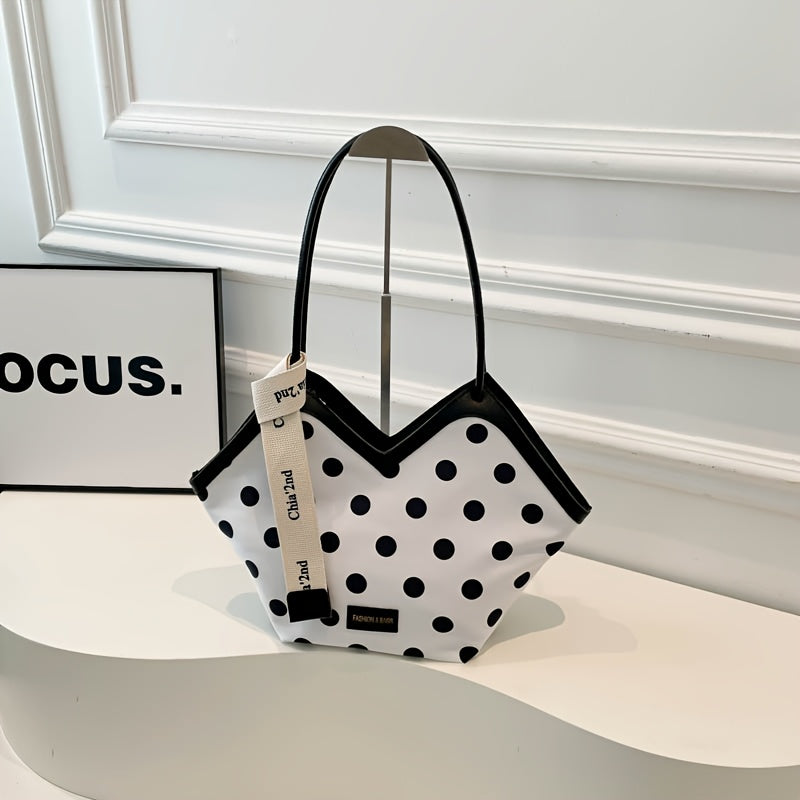 White polka dot shoulder bag with black trim and unique geometric shape, featuring branded ribbon detail